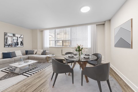 A modern dining room with a glass table and grey chairs.